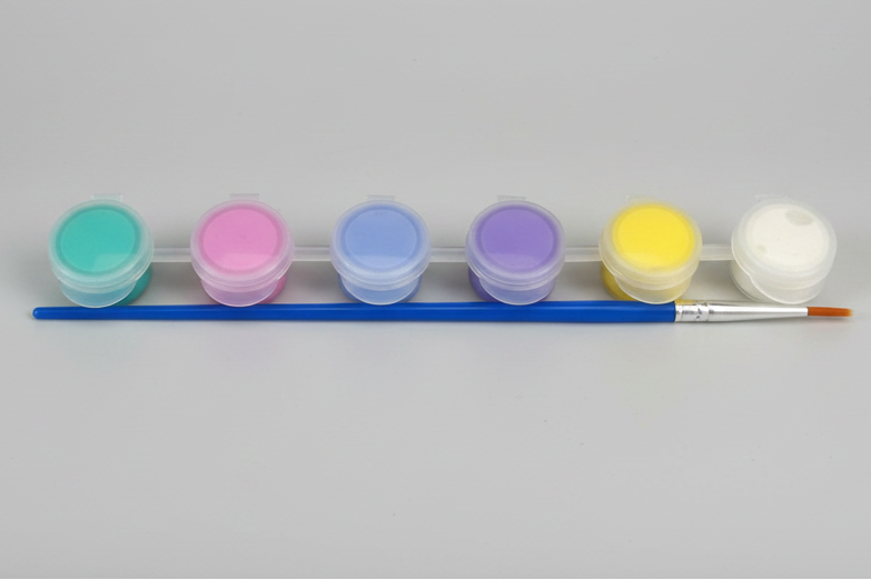 Set of six small paint containers with a brush on a gray background